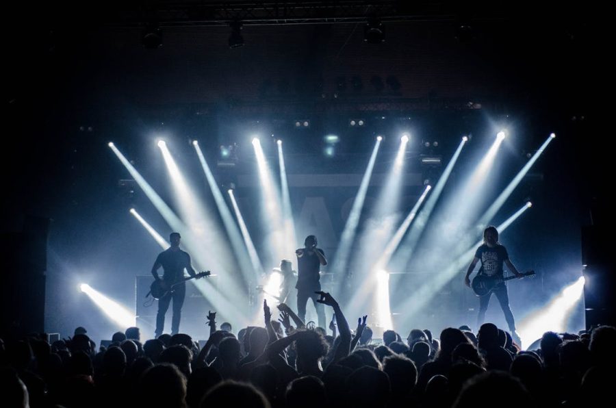A picture of a band performing on stage with lots of spotlights and a large crowd. Created by Thibault Trillet from Pexels.