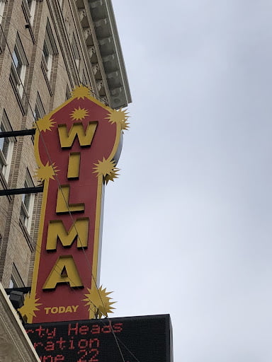 The image shows the Wilma sign. Its mostly red with a yellow outline and lettering. The edge of the building can be seen to the left of the image.