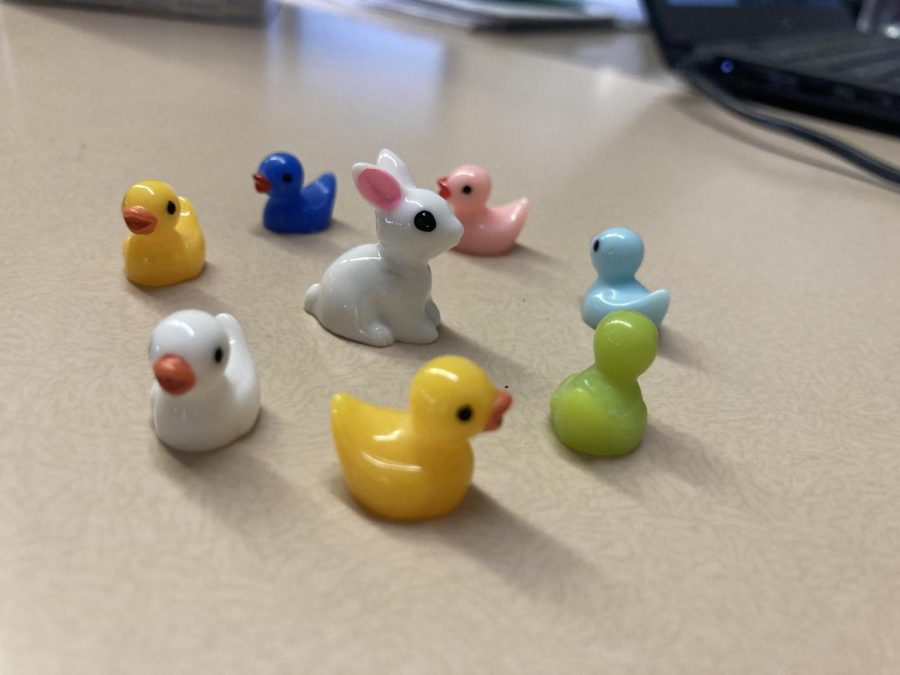 A circle of colorful ducks surrounds a small bunny.
