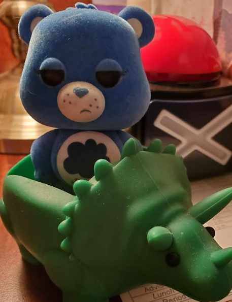 Blue Care bear figurine inside green toy dinosaur.