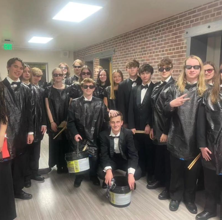 Sentinels percussion ensemble posed in sunglasses, concert wear, and trash bags