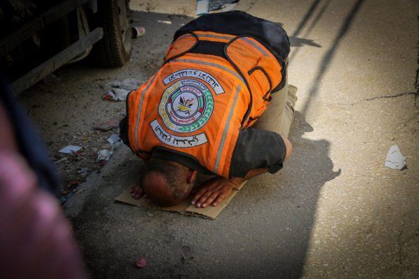 Man Praying on Street for People Under Debris
