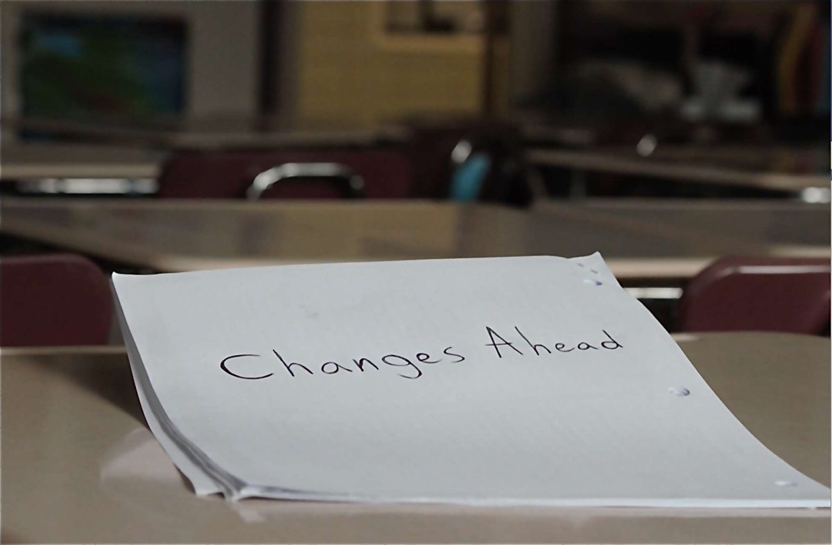 A paper that reads Changes Ahead sitting on top of a classroom desk