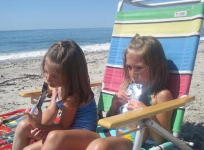 Sadie (l) and Abbie (r) drinking Capri Suns angrily at Carpenters Beach, Rhode Island.
