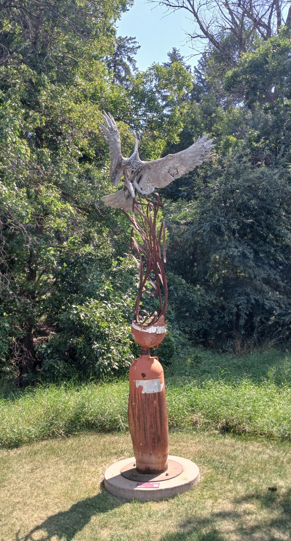 A metallic bird statue in the sun. 