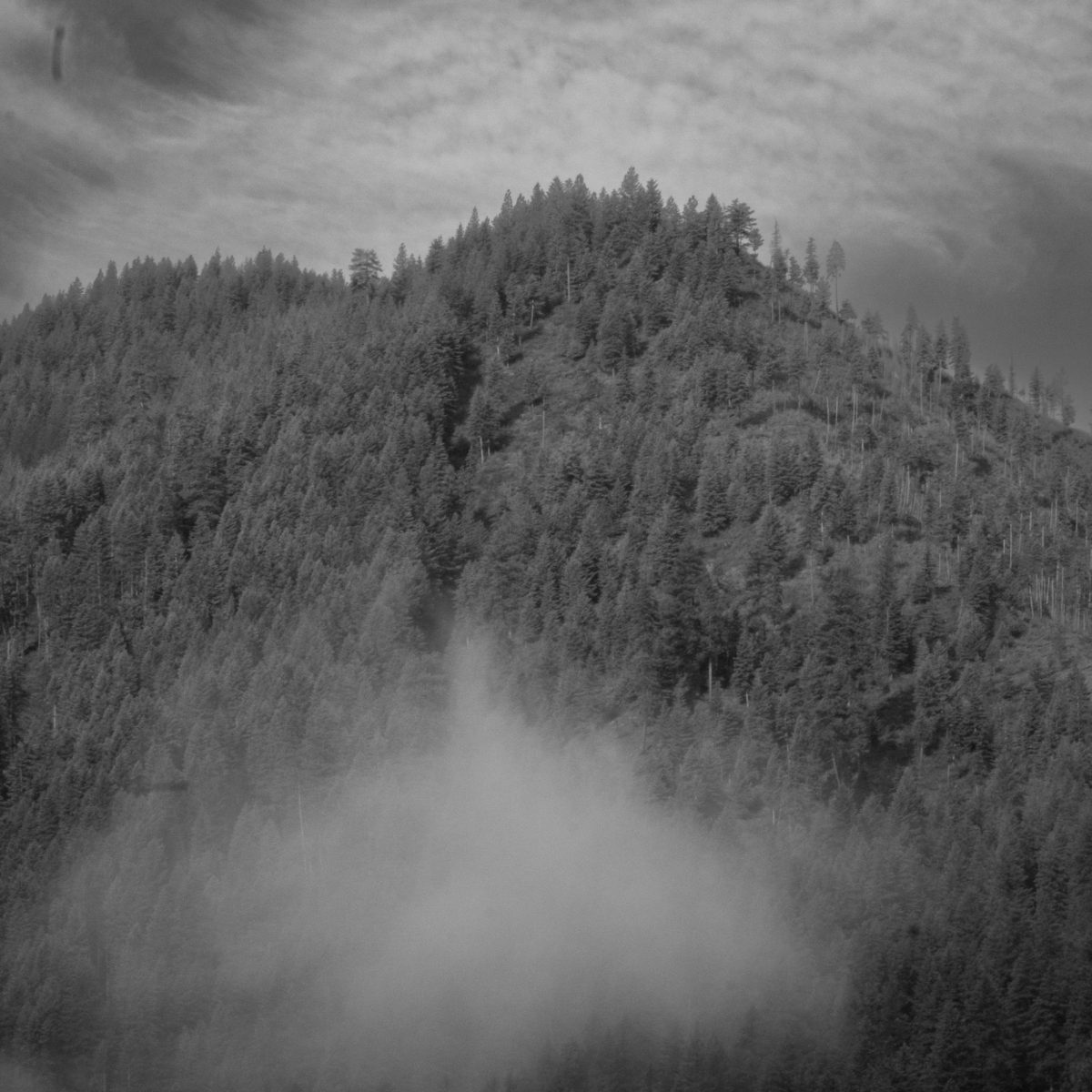 A mountain face accompanied by a cloud