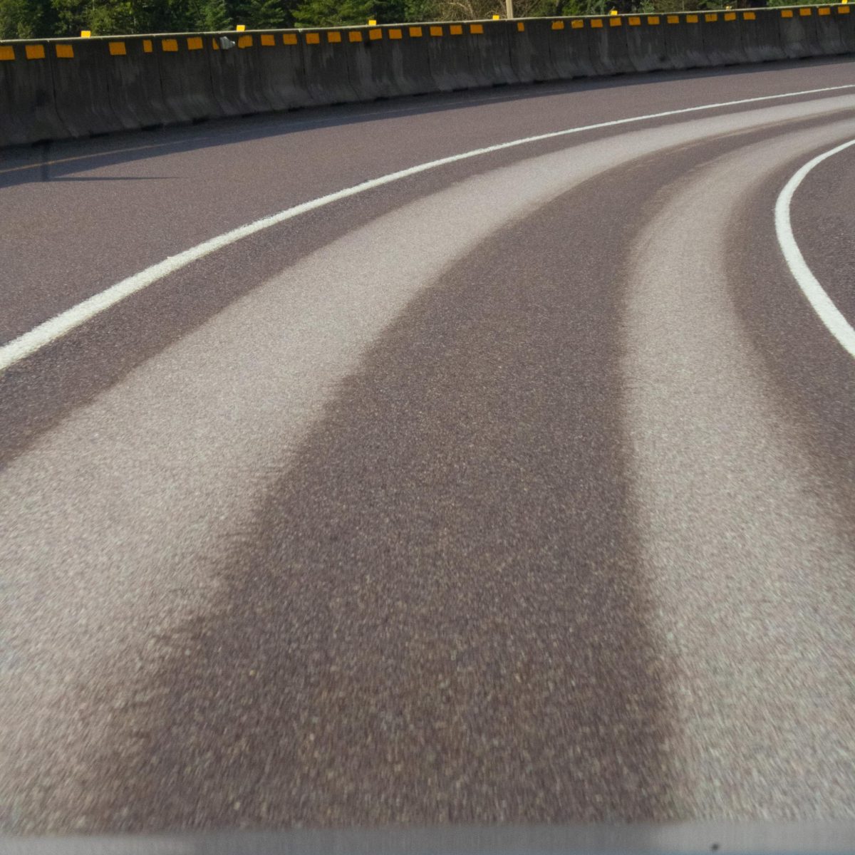 A wet highway with dry tire paths