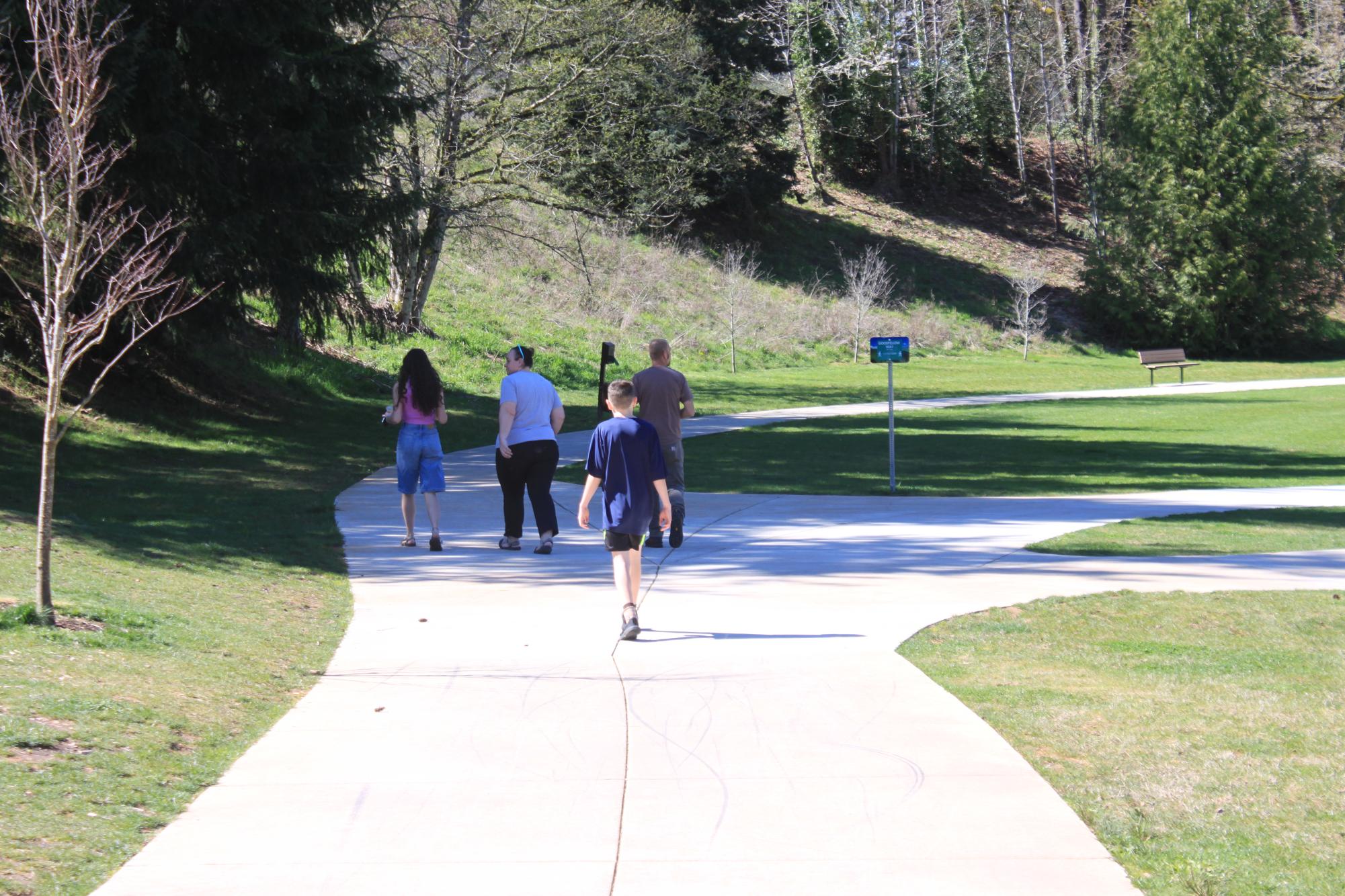 A group of people walking along a path in the park. 